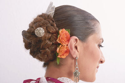 Close-up of woman with flowers against white background