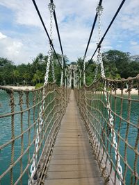 Footbridge over river against sky