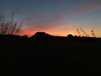 Scenic view of silhouette field against sky at sunset