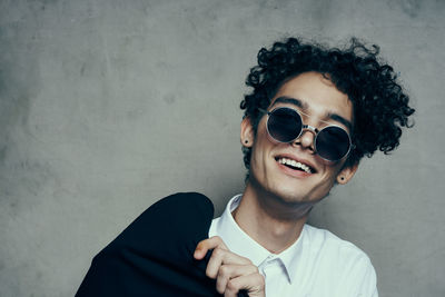 Portrait of young man wearing sunglasses against wall