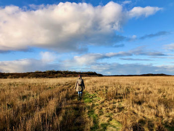Rear view of woman standing on field against sky