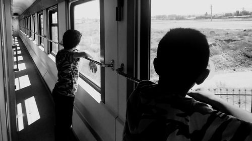 Rear view of boys standing in glass window