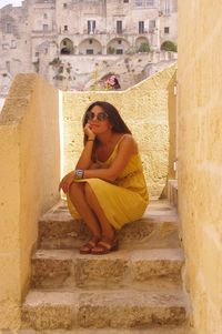 Portrait of woman sitting on staircase against buildings