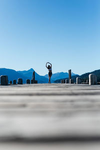 Rear view of woman standing on road against clear blue sky