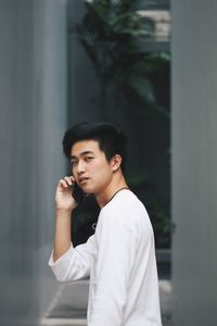 Portrait of young man using mobile phone while standing on street