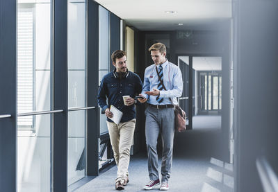 Two colleagues walking and talking on office floor