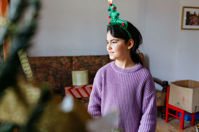 Standing girl with christmas tree headband on the head watching aside