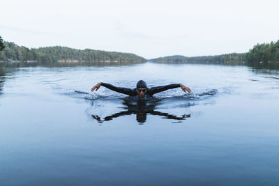 Man with arms outstretched swimming in lake