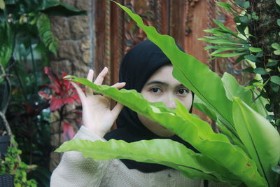 Portrait of young woman hiding plants