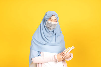 Portrait of person wearing hat against yellow background