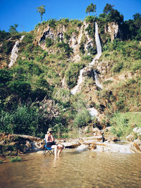 People sitting on rock by water