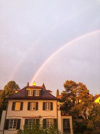 Low angle view of rainbow over buildings against sky