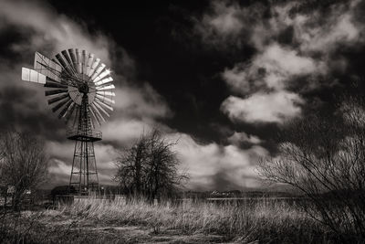 Wind pumping station on field against sky