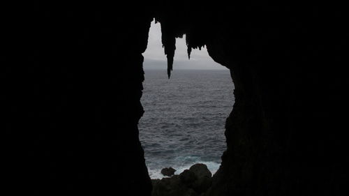 Silhouette rock formations on beach against sky