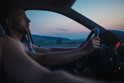 Man with friend driving car during sunset