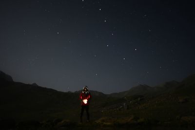 Rear view of man standing on mountain against sky