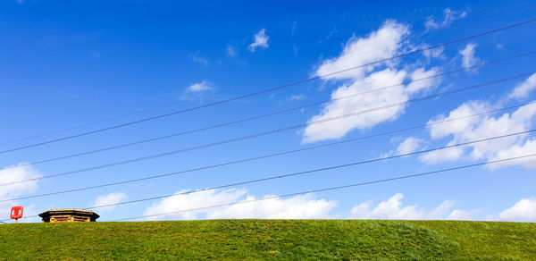 Low angle view of cable car on field against sky