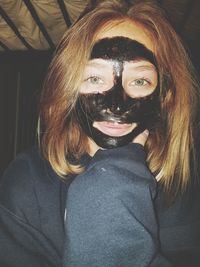 Portrait of teenage girl with black facial mask at home