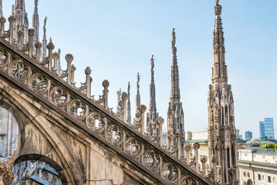 View to spires and statues on roof of duomo through ornate marble fencing. milan, italy