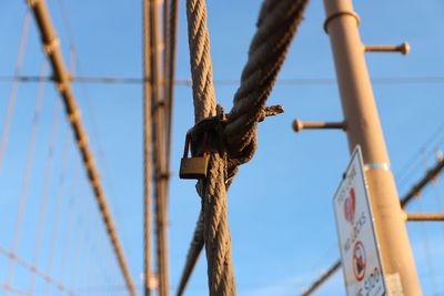 Low angle view of rope tied to pole against sky