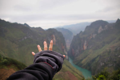 Cropped hand gesturing against valley