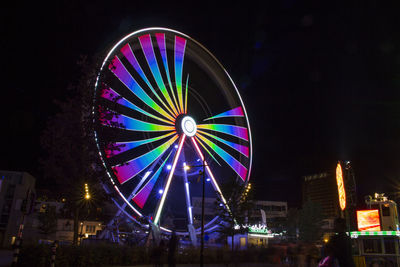 Low angle view of illuminated ferris wheel against clear sky at night