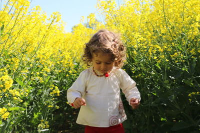 Cute girl with curly hair standing amidst plants