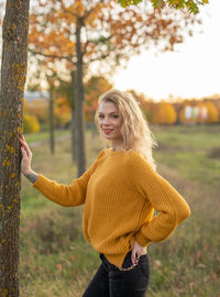 Young woman standing by tree during autumn