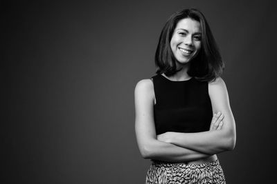 Portrait of smiling young woman against black background