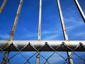 Low angle view of chainlink fence against blue sky