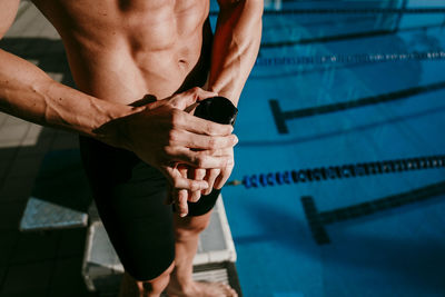 Male swimmer checking smart watch before while standing at poolside