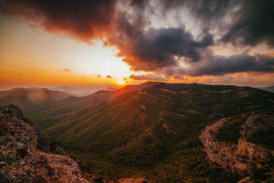 Scenic view of mountains against dramatic sky during sunset