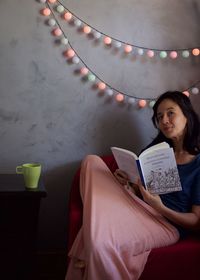 Young woman sitting on book at home