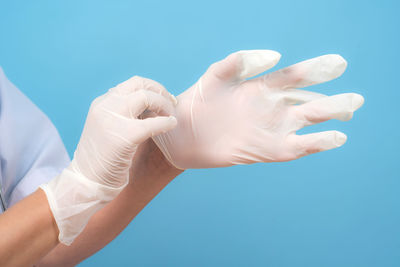 Midsection of woman holding hands against blue background