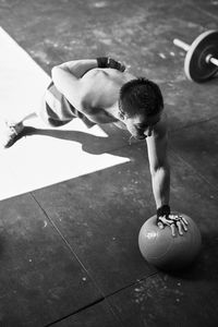 Shirtless fit young man doing one hand push up with a heavy ball