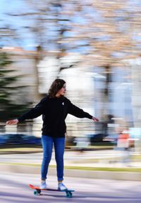 Blurred motion of girl skateboarding on road