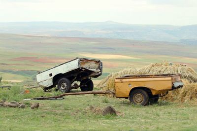 Pick-up truck on grassy field against sky