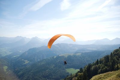 Man paragliding over mountains against sky