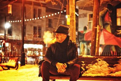 Portrait of man sitting in snow at night