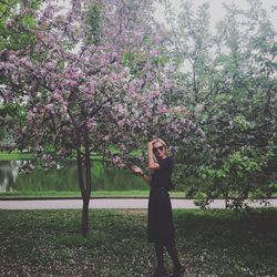 Young woman standing by tree against plants