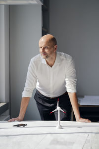 Engineer working in his office with model of a wind wheel on his desk