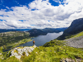 Rear view of hiker standing and looking at summer fjords