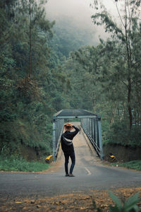 Full length of man standing on road in forest