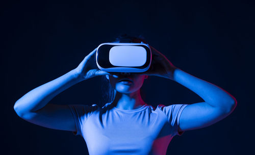 Woman holding camera against black background