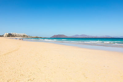 Scenic view of beach against clear blue sky