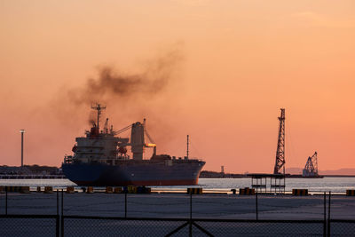 Commercial dock by sea against sky during sunset