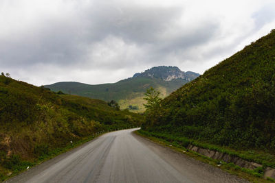 Road leading towards mountains against sky