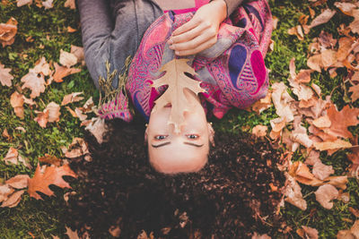 High angle portrait of young woman lying on field at park during autumn