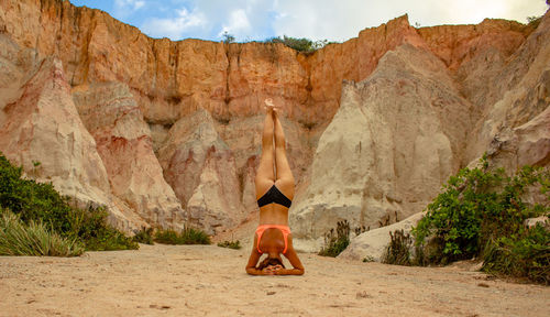 Girl from behind doing yoga handstand in front of a mountain