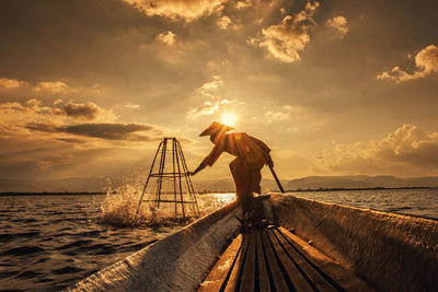 Man standing on sea shore against sky during sunset